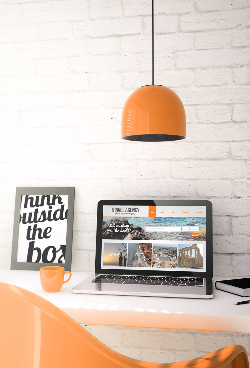 orange desktop with laptop showing travel agency website
